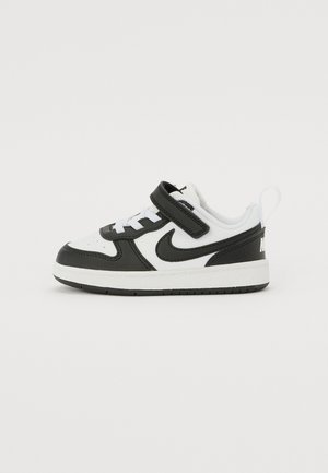 Sneaker bianco e nero con parte superiore in pelle e mesh, cinturino regolabile in velcro, lacci bianchi e colletto imbottito per il comfort.