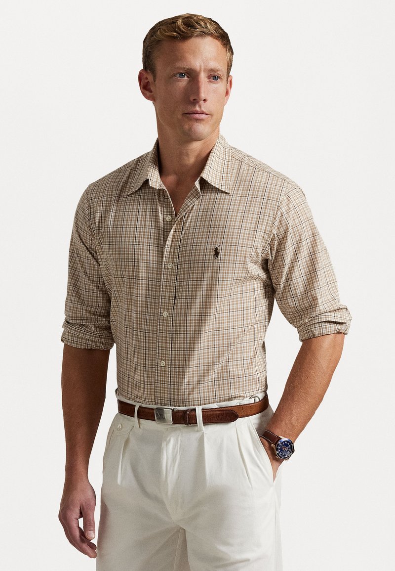 Chemise à manches longues à carreaux dans des tons beige et marron, avec un col boutonné et un petit logo brodé sur la poitrine.