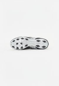 Black-and-white athletic shoe sole with a textured surface, featuring several studs for traction and a patterned design on the side.