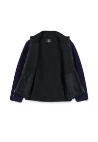 Chaqueta de forro polar con interior negro, cierre de cremallera y material exterior de color púrpura oscuro con un acabado texturizado. Incluye bolsillos con forro de malla.