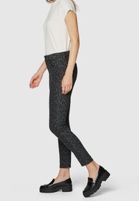 Mustapilkkuiset farkut slim fit -tyylillä, yhdistettyinä yksinkertaiseen valkoiseen lyhythihaiseen puseroon ja mustiin platform-loafereihin. Yksinkertainen ja moderni muotoilu.