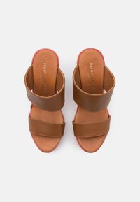 Sandalias deslizantes de cuero marrón con dos correas anchas, borde trenzado rosa y una plantilla de cuero suave. Marca dorada visible en la plantilla.