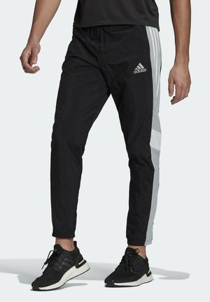 Czarne sportowe spodnie z szarymi akcentami, wykonane z lekkiego materiału. Charakteryzują się zwężanym krojem i elastycznym pasem. Logo adidas po boku.