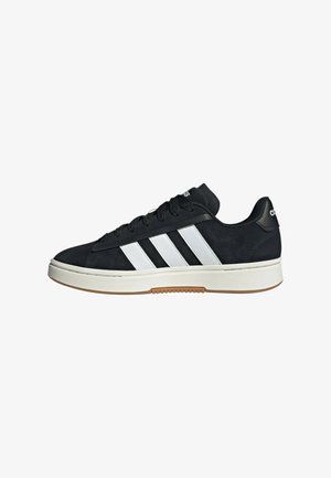 Black Adidas sneaker with white three stripes, black laces, white sole, and gum outsole, shown from the outer side on a white background.
