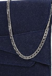 Navy denim clutch met een gestructureerde afwerking, voorzien van een zilveren kettingriem en een gevouwen klepdesign.