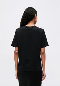 Black cotton T-shirt with a crew neck, short sleeves, and a relaxed fit. Smooth texture, no visible patterns or hardware details.