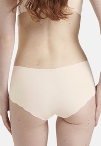 Vaaleanpunaiset saumattomat hipster-allas, joissa on aaltoileva vyötärö ja pehmeä tekstuuri, esittelevät sulavan ja minimalistisen muotoilun.