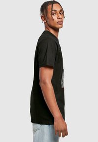 Sort bomulds t-shirt med grafisk print på forsiden og korte ærmer. Designet har grå og røde accenter og en afslappet pasform.
