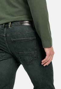 Donkerdenim jeans met een slim fit, voorzien van twee achterzakken, subtiele stiksels en een geweven label op de tailleband.