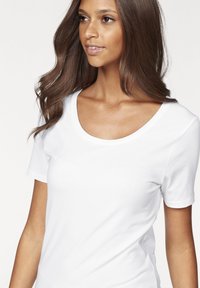 White short-sleeve t-shirt with a scoop neckline, made of smooth fabric, featuring a fitted design that contours to the body.