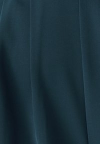 Tumši tirkīza audums ar smalku diagonālu tekstūru, kas piedāvā gludas karājas un maigas krokas. Nav redzamu rakstu vai piederumu.