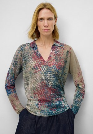 Blusa a maniche lunghe con scollo a V in tessuto trasparente, caratterizzata da un motivo multicolore con punti rossi, blu e verdi su uno sfondo beige.