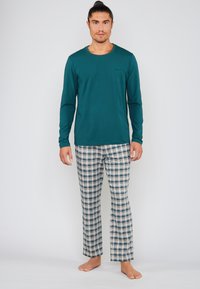 Langærmet skjorte i teal, kombineret med plaid pyjamasbukser i blå, grøn og hvid. Blødt stof og afslappet pasform.