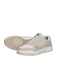 Sneaker beige con una toma superiore in sintetico liscio, accenti perforati, suola bianca e logo nero sulla linguetta; progettate per un uso casual.
