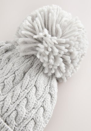 Hall hallatud müts tugeva tekstuuriga punutud mustriga ja suure, koheva tupsuga peal. Pehme, soe materjal sobib külma ilmaga.