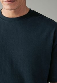 Donkerblauwe katoenen t-shirt met een ronde halslijn en korte mouwen, met een gladde textuur en eenvoudig ontwerp. Minimaal zichtbare branding.