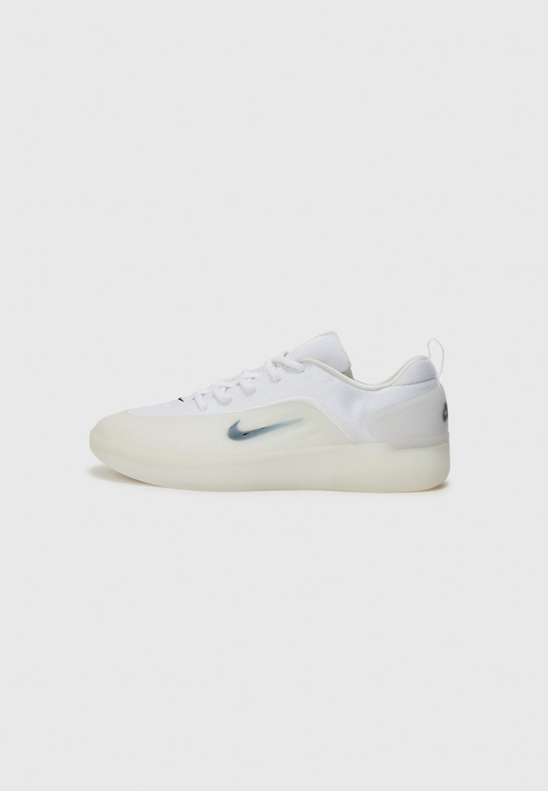 Baskets blanches avec une semelle en caoutchouc lisse et une tige en mesh, présentant un logo Nike bleu évasé sur le côté et un talon texturé.