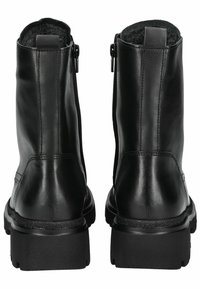 Stivali alla caviglia neri in pelle con zip laterali, foderati in pelliccia sintetica testurizzata e suole in gomma spessa. Design minimalista con finitura liscia.