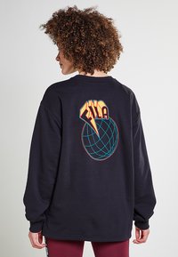 Felpa nera a maniche lunghe con un logo geometrico colorato sulla schiena. Materiale in cotone, vestibilità comoda, collo a costine e maniche con polsini.