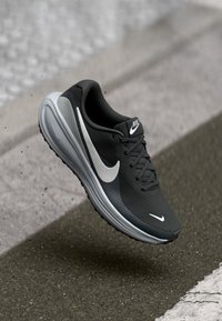 Scarpa sportiva nera con tomaia in mesh testurizzato, logo Nike bianco e suola grigia, dotata di lacci e colletto imbottito.