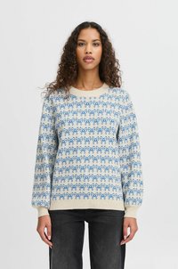 Suéter de crema claro con patrones de lazo azul. Puños y dobladillo acanalados. Textura suave, escote redondo y ajuste ligeramente holgado.