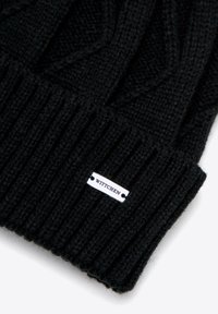 Czarna dziana czapka z prążkowaną fakturą. Posiada przyszywaną metkę z napisem "WITTCHEN" na białym, prostokątnym metalowym znaczku.