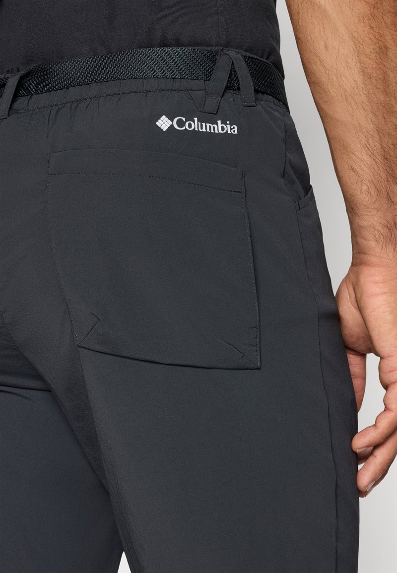 Schwarze Columbia-Hosen aus strukturiertem Material, mit einer hinteren Taschenpatte und einem gewebten Gürtel. Das Logo ist in Weiß auf der Rückseite aufgedruckt.