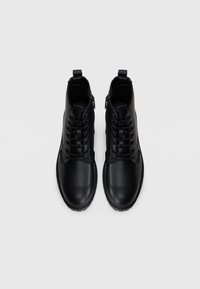 Stivaletti neri in pelle liscia, con una finitura lucida, caratterizzati da una chiusura con lacci, cerniera laterale e punta arrotondata.