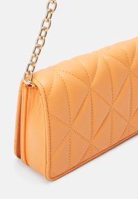 Pikowana pomarańczowa skórzana torebka na łańcuszku, ozdobiona geometrycznym przeszyciem i posiadająca prostokątny kształt. Gładka faktura.
