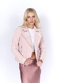 Veste de moto en suede rose clair avec poches zippées, fermeture éclair asymétrique à l'avant et coupe ajustée, associée à une jupe en satin rose.