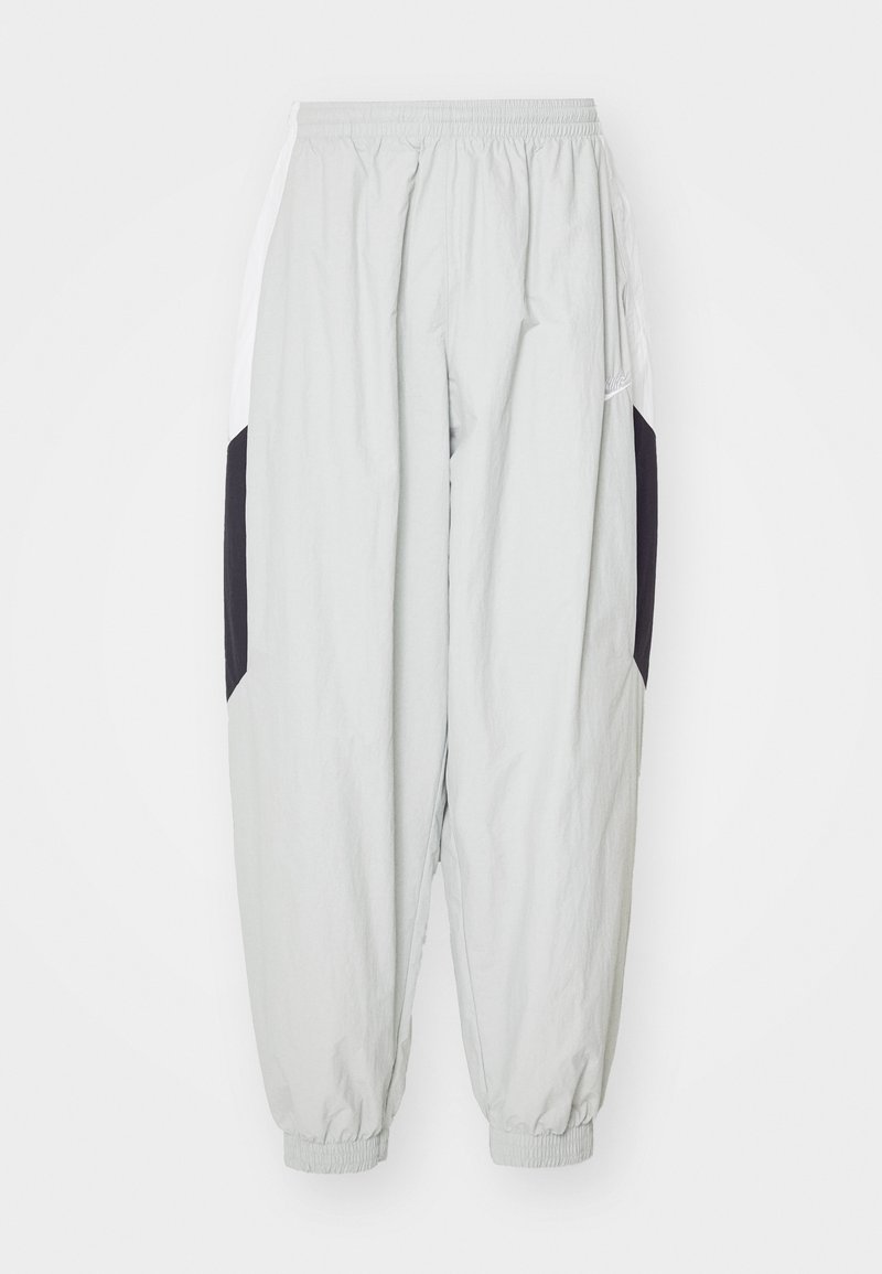 Pantalons de jogging gris clair en tissu léger, avec taille élastique et poignets, dotés de panneaux latéraux contrastants noir et blanc.