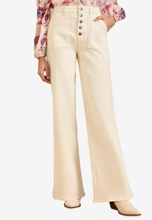 Pantalons larges en crème en tissu texturé avec une taille haute. Comprend cinq boutons métalliques et deux poches avant.