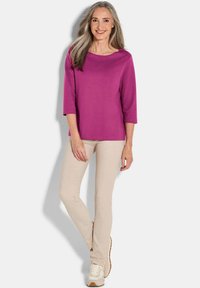 Fuchsia 3/4 mouw top met een brede halslijn, gecombineerd met beige, strakke broek en lichte sneakers. Gladde textuur, casual ontwerp.