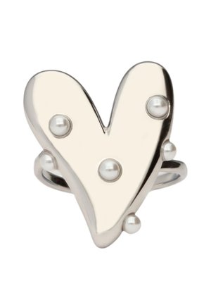 Anillo plateado en forma de corazón decorado con pequeñas perlas redondas sobre un fondo blanco liso.