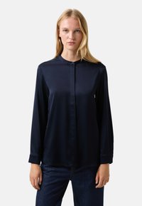 Marineblauwe satijnen blouse met een knoopsluiting aan de voorkant, een klassieke kraag en lange mouwen, voorzien van een gladde textuur en een ontspannen pasvorm.