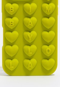 Żółta silikonowa etui na telefon z wypukłymi kształtami serc i literami zapisującymi "BABY LAYLA", o gładkiej fakturze i zaokrąglonych krawędziach.