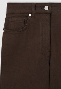 Nahaufnahme von dunkelbraunen Jeanshosen mit Vordertasche, Münztasche, Gürtelschlaufe und silbernem Knopfverschluss.