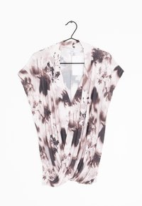 Haut en tissu floral doux et léger. Présente un design drapé avec un col en V, des manches courtes et un mélange de teintes roses et marron.