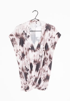 Top in tessuto floreale morbido e leggero. Presenta un design drappeggiato con scollo a V, maniche corte e una combinazione di tonalità rosa e marrone.