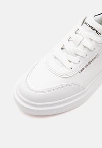 Baskets en cuir blanc à lacets avec semelle épaisse et marquage "Karl Lagerfeld" sur la languette et le côté.