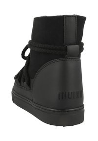 Bota de tobillo de cuero negro y ante con cordones trenzados, punta redonda, acentos texturizados y logo "INUIKII" en el talón.