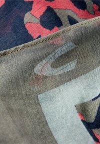 Letvægtsstof med et camouflage-mønster i nuancer af marineblå, olivengrøn og koral, med en glat tekstur og syede kanter.