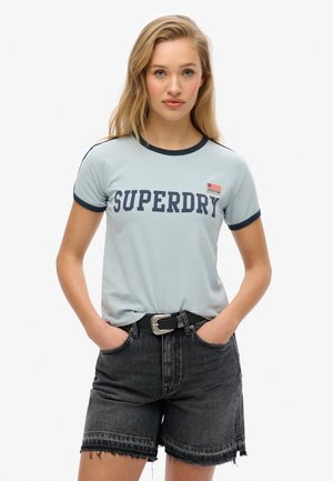 T-shirt léger bleu clair à manches courtes avec des finitions navy et l'inscription "SUPERDRY". Associé à un short en denim noir taille haute et une ceinture décorative à boucle.