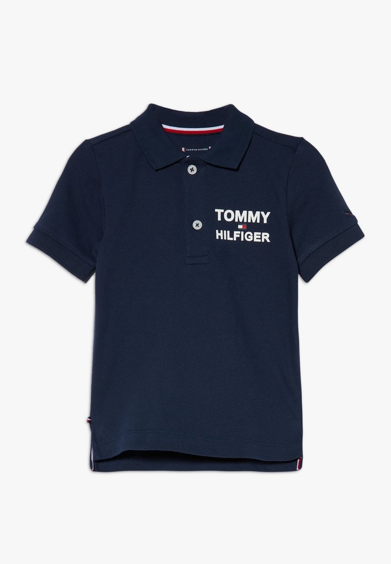 Námořnická modrá polokošile z bavlny, s třemi knoflíky po celé délce a logem "TOMMY HILFIGER" v bílé barvě na levém prsu. Krátké rukávy.