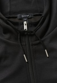 Felpa nera con zip e colletto alto, dotata di zip argentata, lacci neri e un'etichetta con "Matinique" e taglia L.