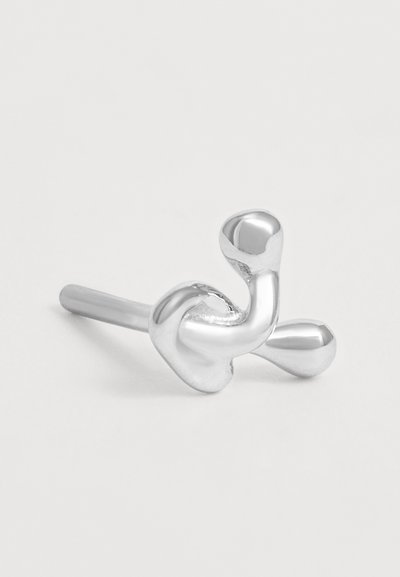 Clou d'oreille en forme abstraite torsadée argentée sur un fond clair uni, montrant le détail avant et la tige droite.