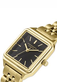 Orologio da polso quadrato color oro con quadrante nero, indicatori e lancette dorate, e il marchio "Copenhagen Studios" sul quadrante.