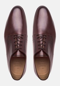 Ein Paar polierte dunkelbraune formelle Schnürschuhe aus Leder mit glatter Oberfläche und genähten Details, von oben betrachtet.