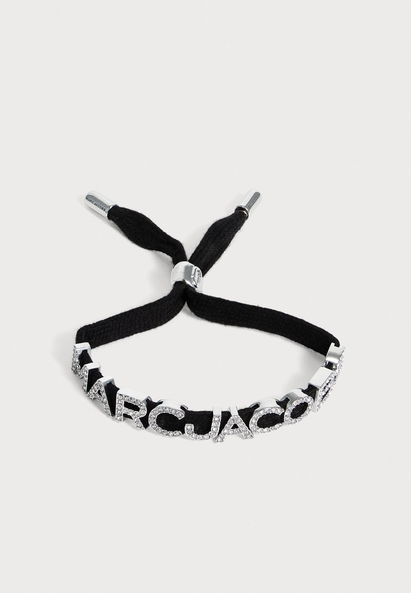 Bracelet en tissu noir avec des lettres en argent incrustées de cristaux formant le mot "MARC JACOBS" et des extrémités de fermoirs coulissants en métal réglables.