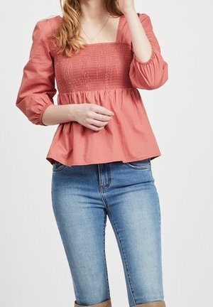 Broskvově zbarvená halenková halenka s čtvercovým výstřihem a nařaseným živůtkem, s dlouhými nafouknutými rukávy a měkkou, texturovanou tkaninou.